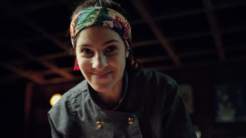 A woman indoors wears a headband and jacket smiling
