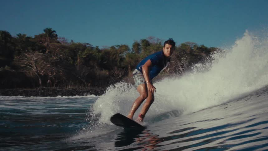 The man cuts across the blue wave on his surfboard