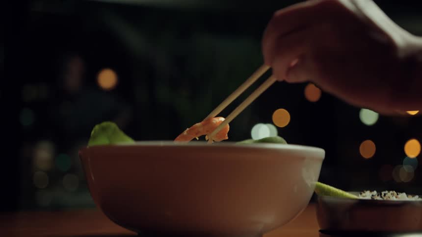 A person picks up shrimp with chopsticks