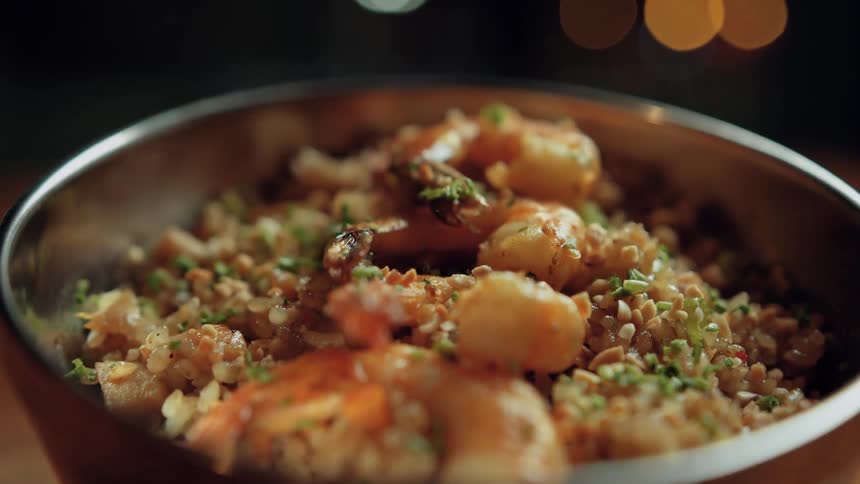 A bowl of rice with shrimp is placed on a dining table