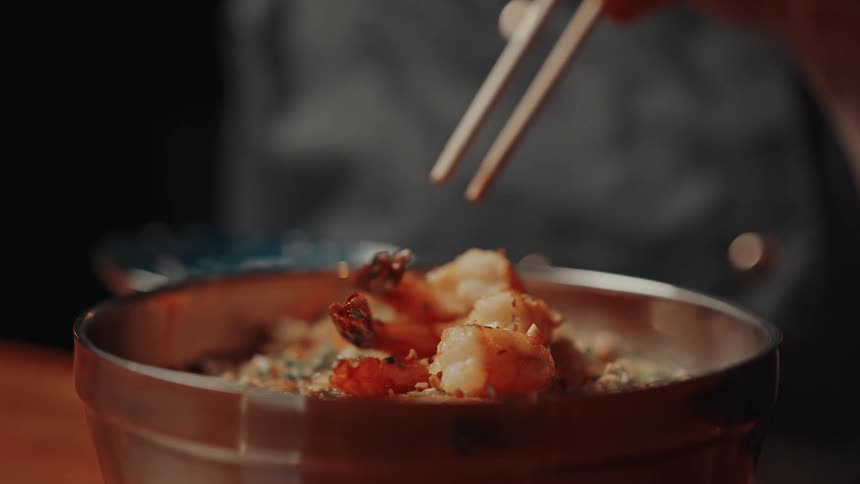 The chef is plating the shrimp onto the dish