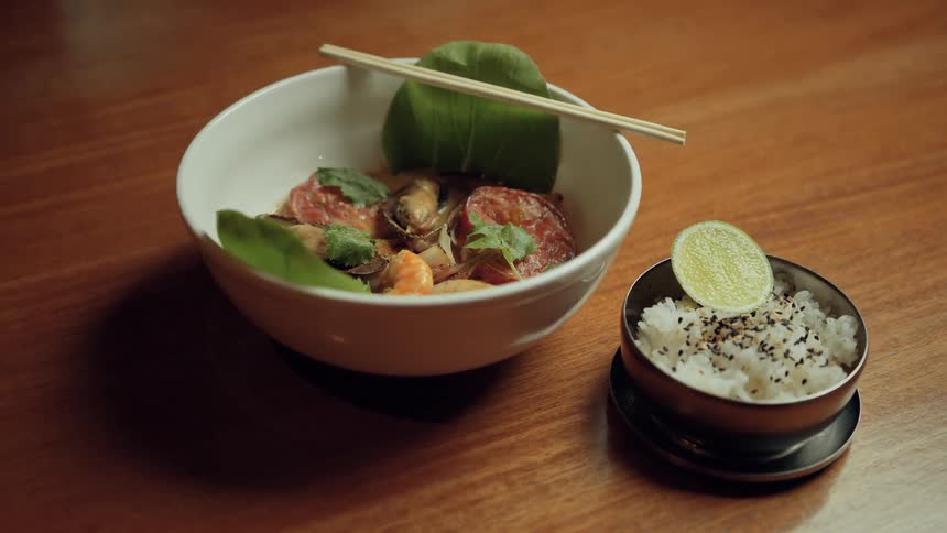 Asian food being presented in two bowls on a wooden table