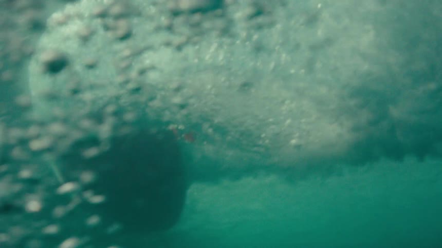 A young man surfs across the sea surface during daytime