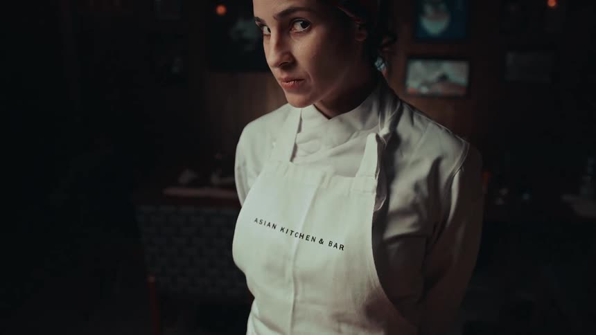 The video shows a person wearing a white chefs coat or apron with their head slightly bowed and looking down a filmsupply watermark is visible in the center of the frame