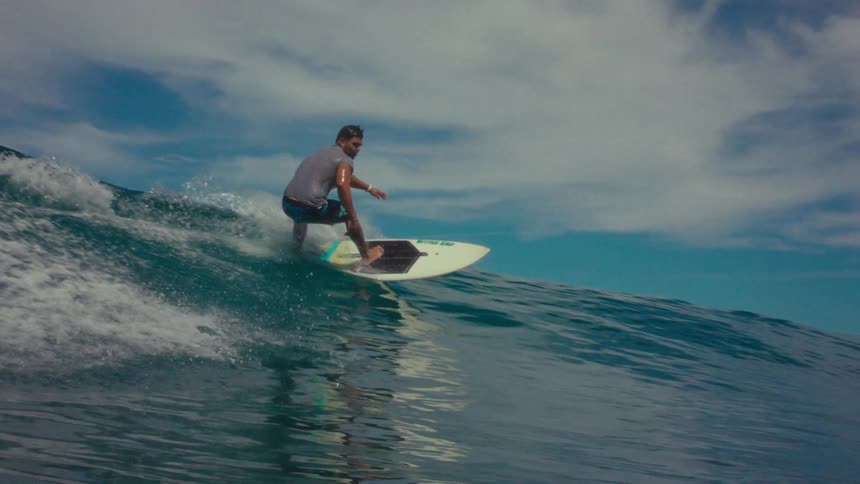 A man on a surfboard surfs a large wave in the ocean like a pro