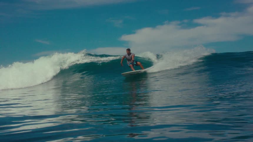A surfer rides a wave on a sunny day in the ocean