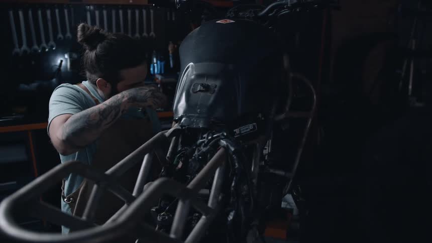 A male mechanic works on a motorcycle inside a factory