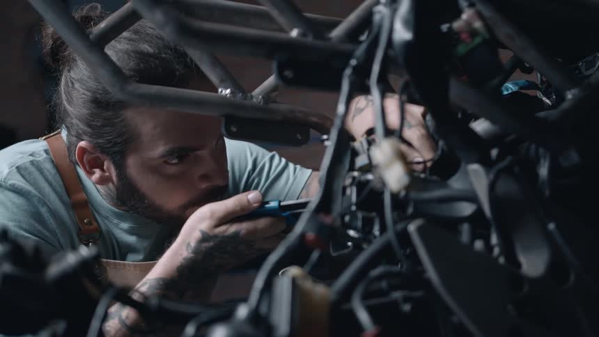 Close up of a male mechanic working on a motorcycle in a workshop during daytime