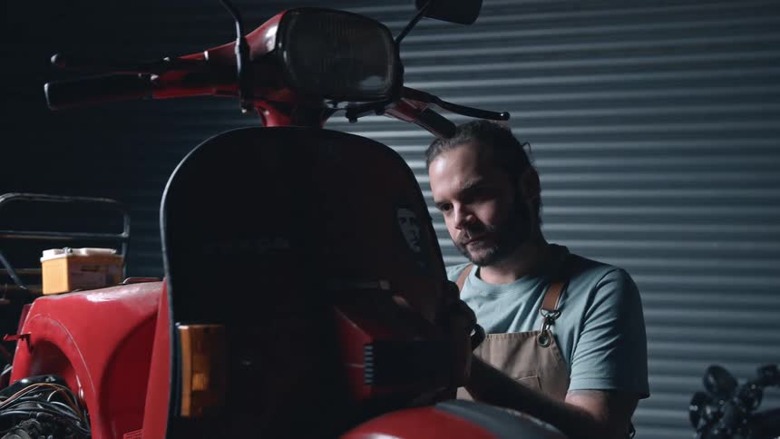 A mechanic works on a scooter in his workshop
