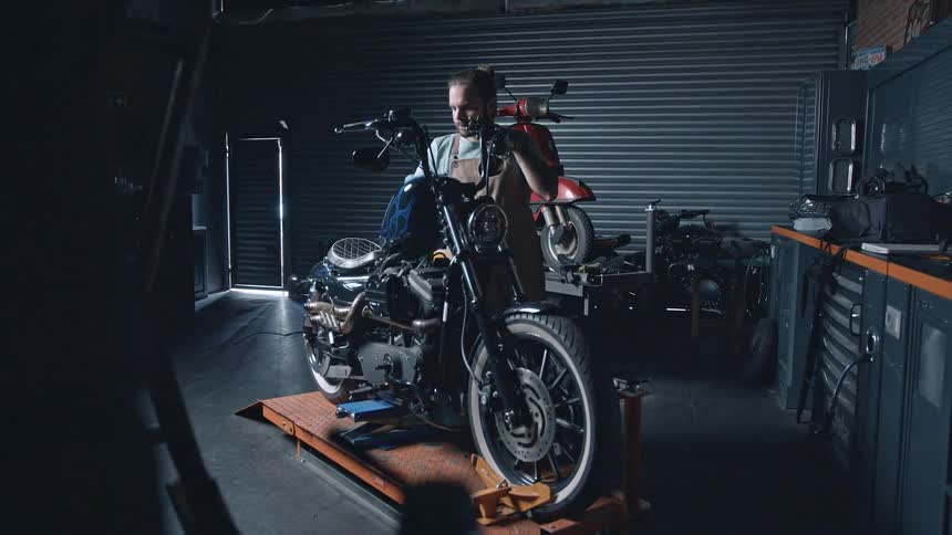 Mechanic working on a motorcycle in a garage with workshop