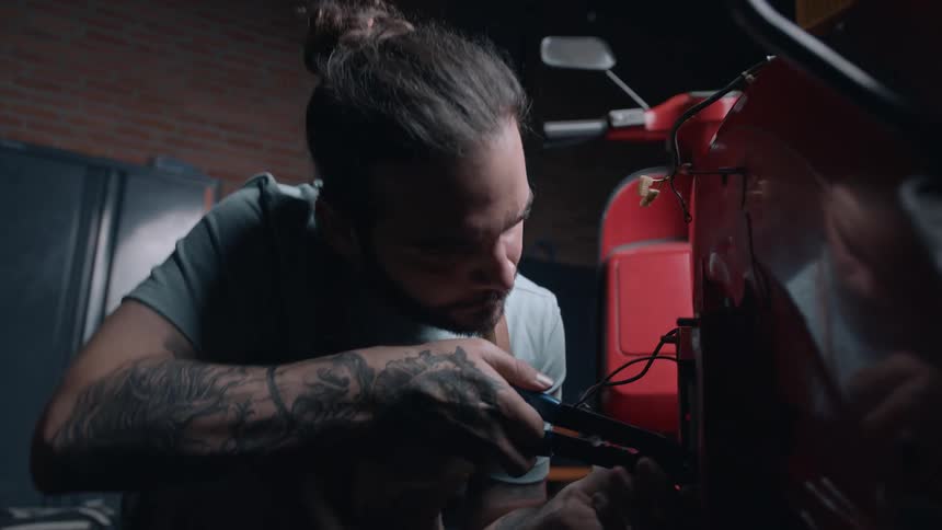 A focused mechanic works on a vehicle in a dimly lit garage