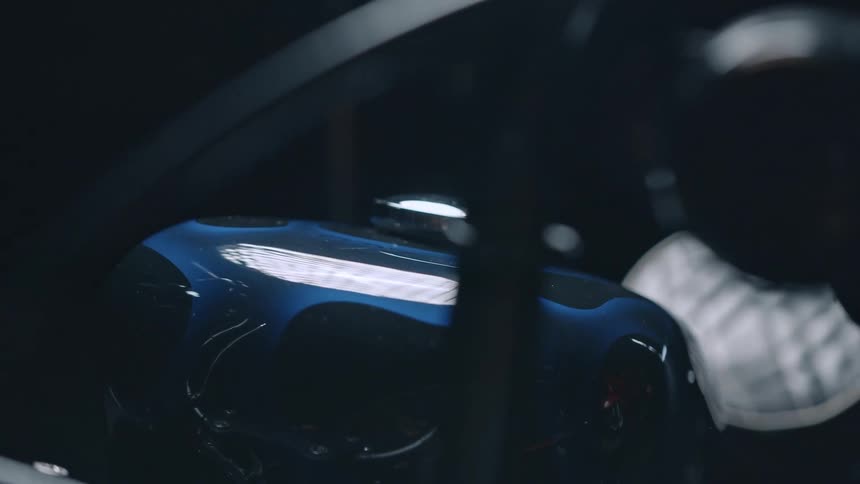 This video features a closeup artistic shot of a motorcycles fuel tank showcasing its sleek design and vibrant blue color with reflective accents the dark moody lighting of what appears to be a workshop or garage creates a sense of intrigue and high