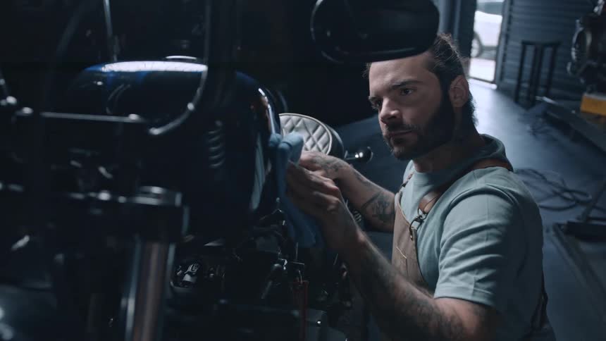 The man is polishing the side of the motorcycle