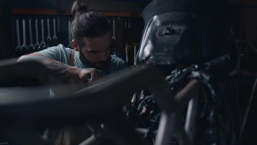 A mechanic uses a wrench to tighten a bolt while working on a motorcycle