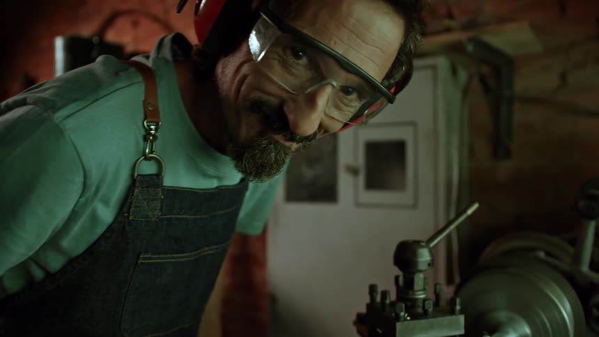 Male lathe operator with happy expression working on a machinery