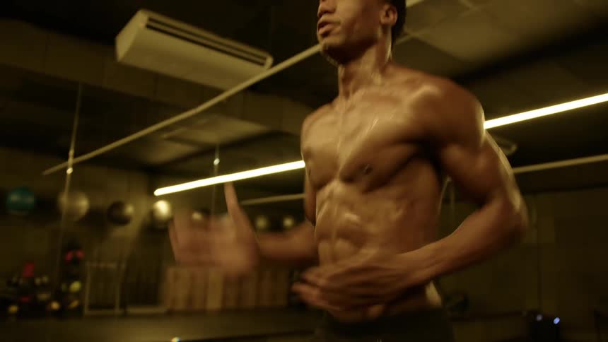 A shirtless man jogs in place in the gym