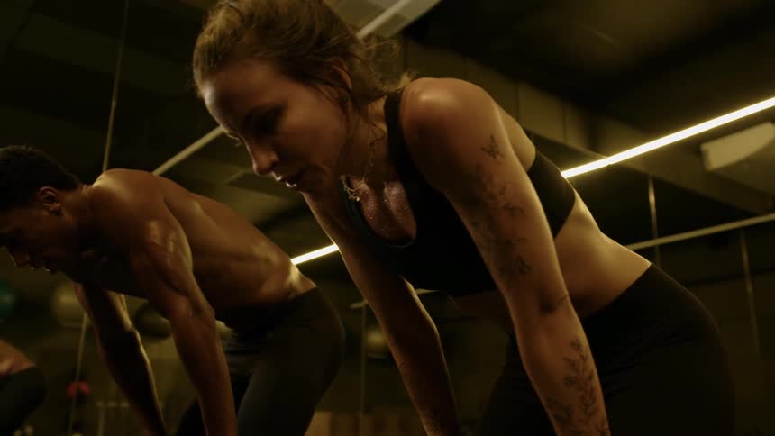 A man and a woman catch their breath after an intense workout in the gym