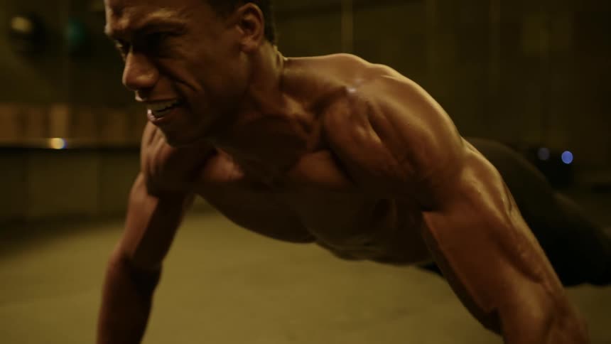 Strong fit male doing push ups on floor at the gym