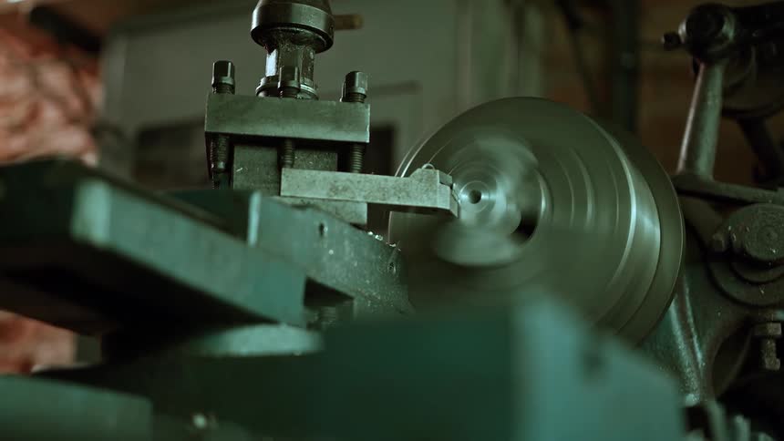 A metal lathe spins rapidly as it shapes a part in a workshop setting