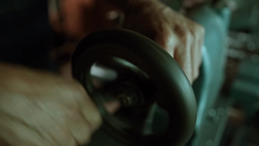 Persons hand turning a crank of a manual machine