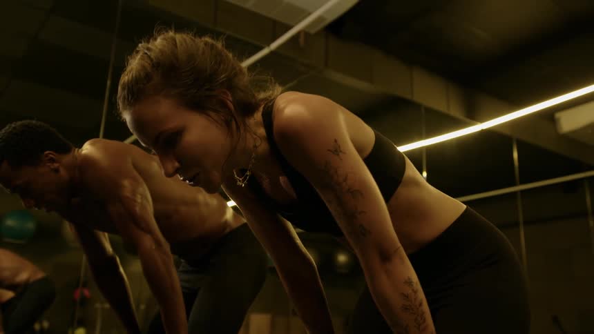 A man and a woman in the gym catch their breath exhausted from exercising