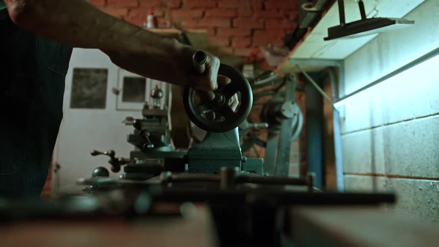 Close up of a man operating a machine on a worktop in a workshop