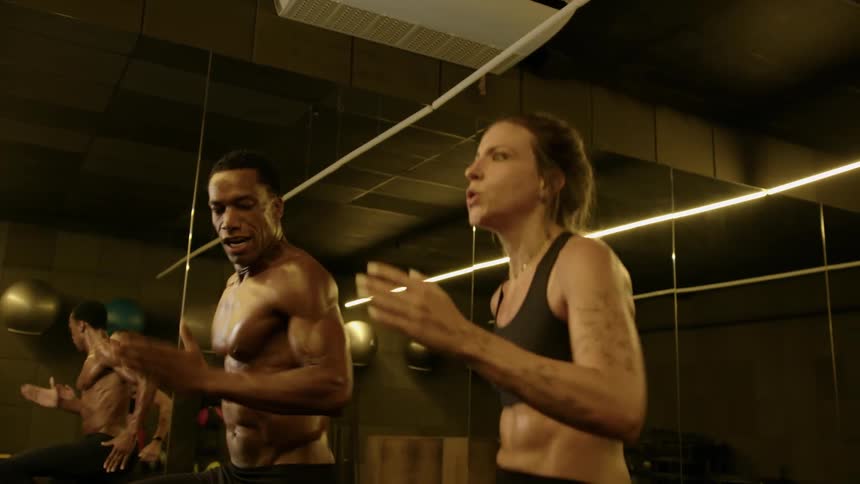 A man and a woman work out side by side jogging in place