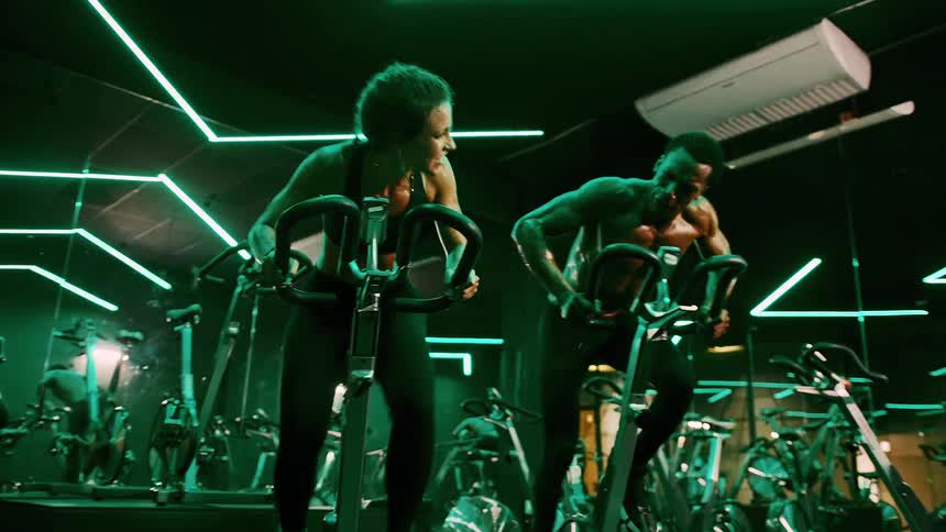 A young man and woman exercise with gym bikes in the gym