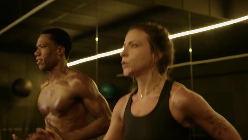 Woman and man work out intensely in a mirrored gym