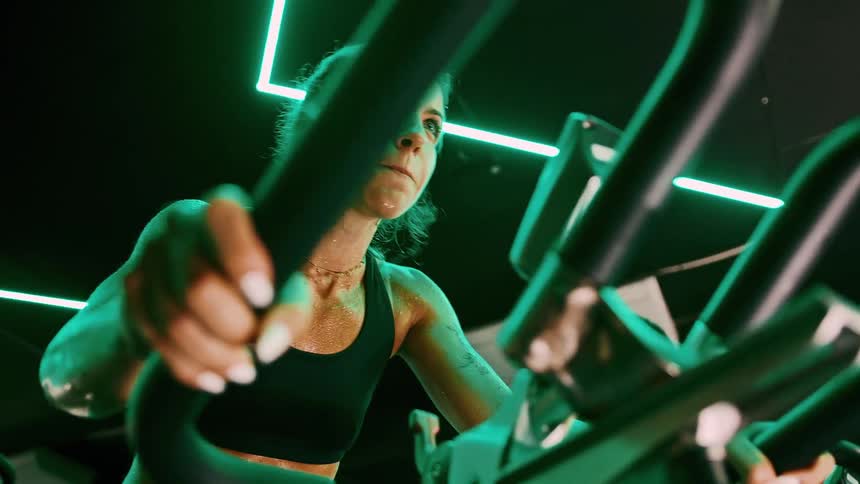A young woman and a man cycle with determination on stationary bikes in the gym