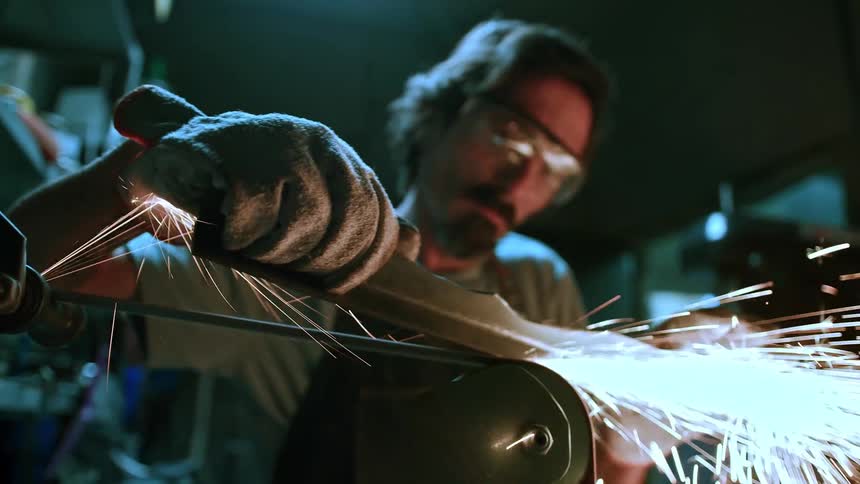 A man creates a stream of sparks while grinding a piece of metal