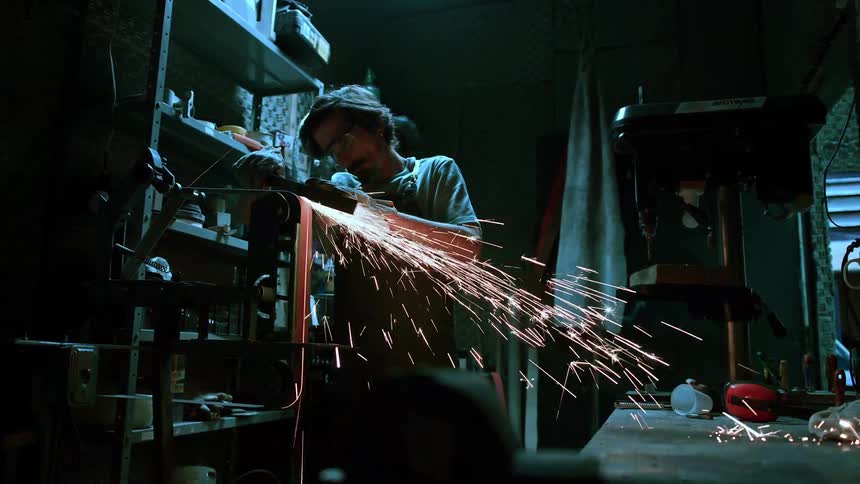 Man working as a lathe operator scraping metal on a machine