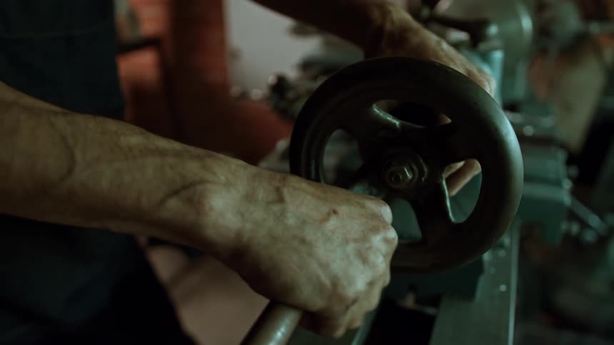 The man turns the wheel on the drill