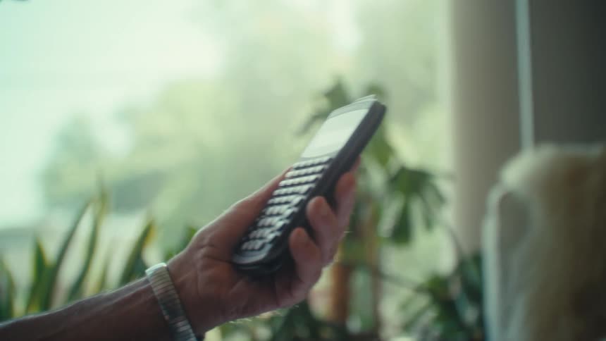 Close up of an elderly man using a calculator while working at a table in a room during daytime