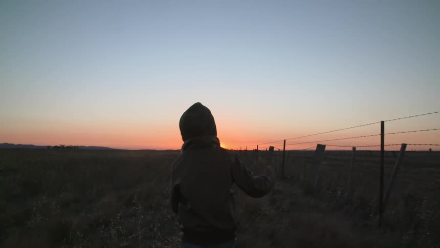 Child running through a field at sunset