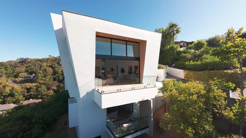 A sunlit urban home is surrounded by trees and features a modern interior