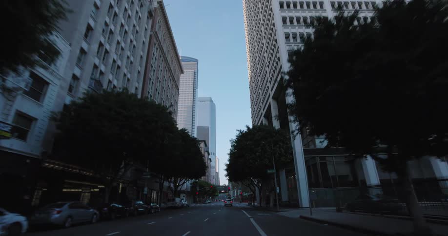 A car drives along a city street lined with many tall buildings