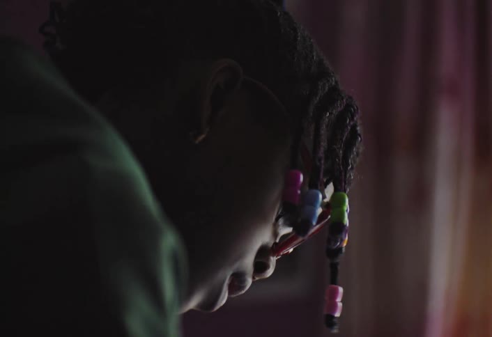 Dreadlocked child with colorful clips in an indoor space