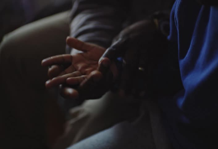A closeup shows an older man holding a childs open palm while someone offcamera points at the lines on the childs hand