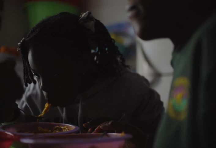 Two kids eat spaghetti at the dining table indoors
