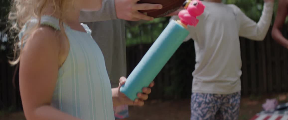 Children of various ages holding toys in a backyard