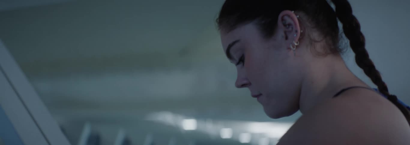 Female swimmer walks through a natatorium while frowning