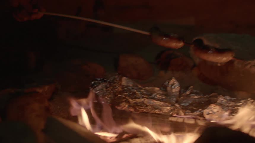 Sausages being cooked over a campfire