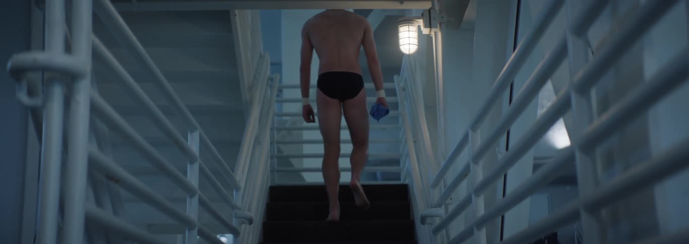 Man in swimming trunks walking up the stairs