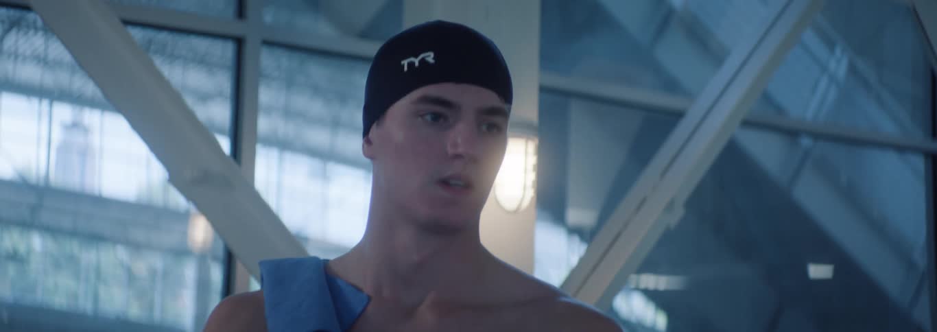 Male swimmer walks through a natatorium located in the city during the daytime
