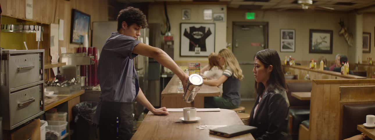 The video shows a male waiter pouring coffee for a female customer in a diner in the background other customers are seated in booths and a filmsupply watermark is visible across the screen