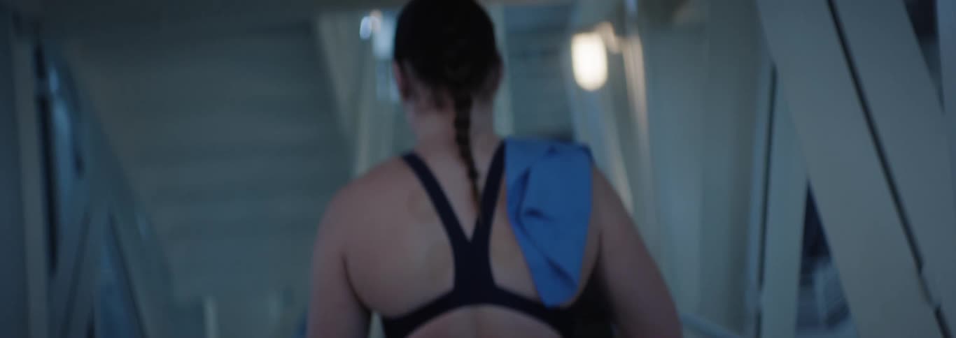 Woman from behind climbing the stairs in an interior space