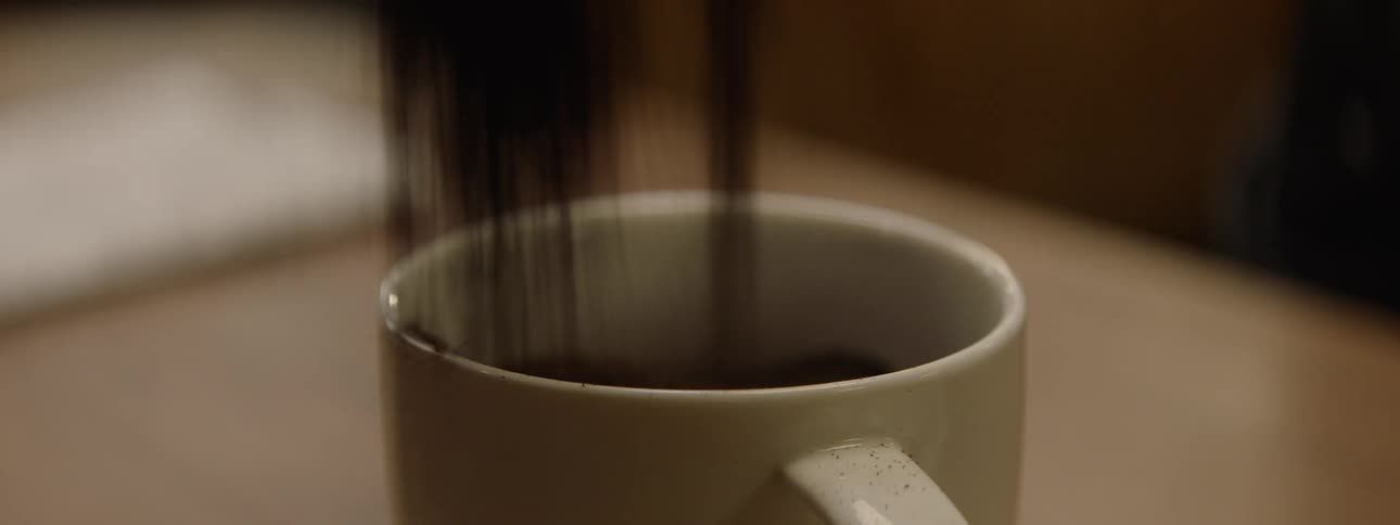 Ground coffee is poured into a mug