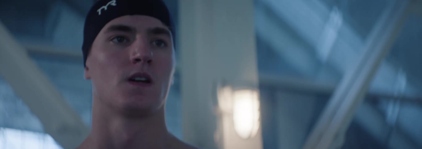 A male athlete wears headgear inside a large pool area