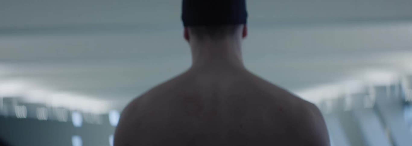 The video shows the bare upper back of a person likely a male with visible shoulder blades and neck the lighting is subdued highlighting the contours of the muscles